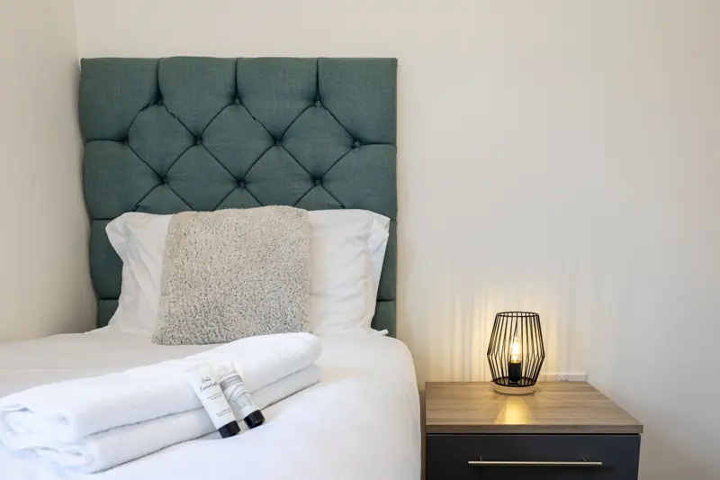 Single bed with towels and lamp